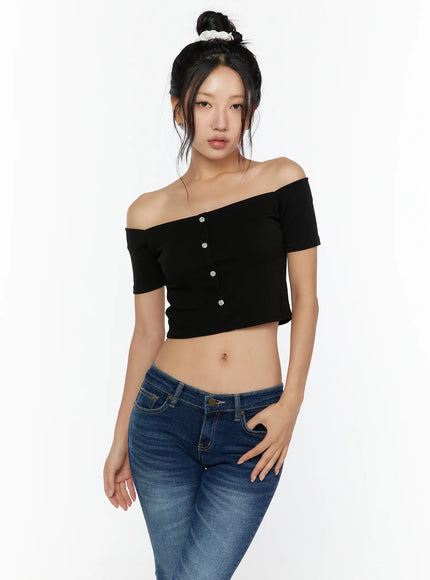 Off-Shoulder Crop Top CU529 Black front model half-body shot, direct camera gaze, ribbed knit off-shoulder top with silver buttons and blue low-rise jeans