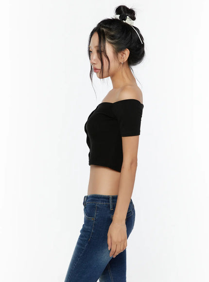 Off-Shoulder Crop Top CU529 Black side model shot showing off-shoulder sleeve and cropped silhouette, model gazing down with bun hairstyle and blue jeans