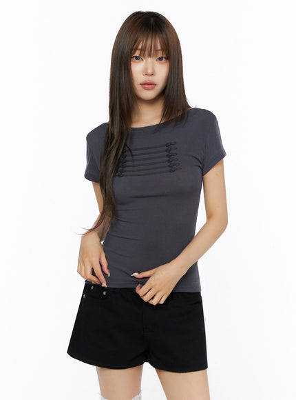 Off-Shoulder Crop Top IL523 charcoal gray front shot on model wearing black shorts, crew-neck short-sleeve tee with tonal horizontal cord and button embellishment