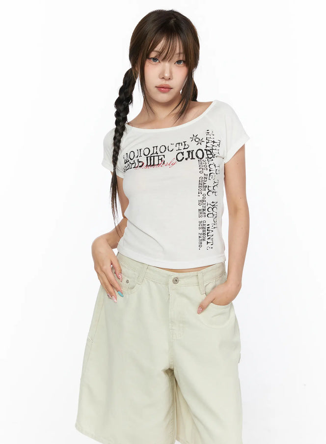 LEWKIN Off-Shoulder Graphic Crop Short Sleeve Tee CL514 White front view on model wearing braided pigtails paired with beige wide-leg shorts