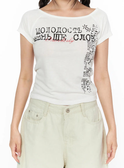 Off-Shoulder Graphic Crop Short Sleeve Tee CL514 White close-up front detail shot showing wide boat neckline Cyrillic graphic print and soft jersey fabric texture