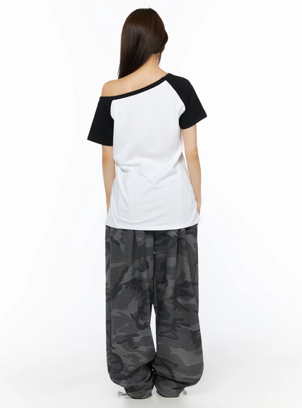 Off-Shoulder Graphic Print Top IL523 White back shot on model showing plain white back black raglan sleeves asymmetric neckline relaxed fit paired with camo pants