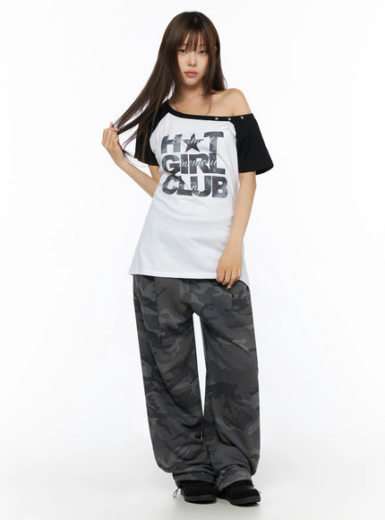 Off-Shoulder Graphic Print Top IL523 White full-length front shot on model standing straight black raglan sleeves star stud asymmetric neckline camo pants