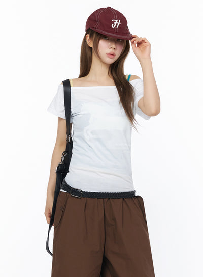 LEWKIN Off-Shoulder Graphic Short Sleeve Top IU525 White S/M front shot on model styled with burgundy cap and crossbody bag, layered bra straps visible
