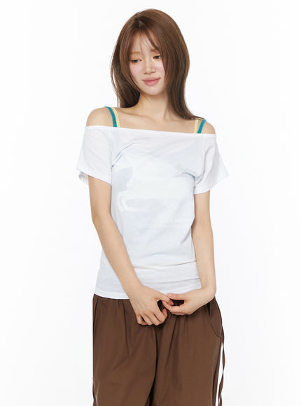 Off-Shoulder Graphic Short Sleeve Top IU525 White close-up front shot on model with hands clasped, horse graphic print detail, layered teal and beige bra straps