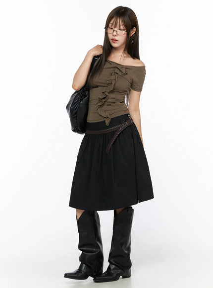 Off-Shoulder Ruffle Tee CL517 Dark beige full-body front shot on model holding black bag over shoulder, glasses on, styled with black midi skirt and knee-high cowboy boots