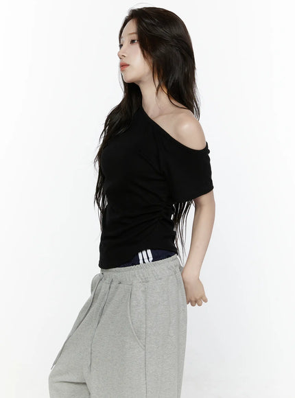 Off-Shoulder T-Shirt IL522 Black side shot on model profile view, asymmetric off-shoulder neckline, ruched body, cropped silhouette