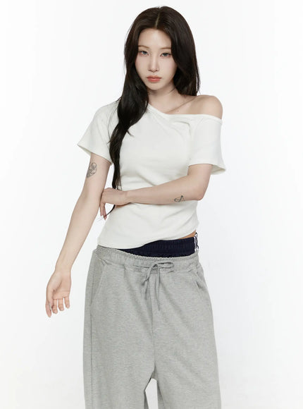 Off-Shoulder T-Shirt IL522 White three-quarter front shot on model with arms crossed, one-shoulder neckline and ruched waist detail