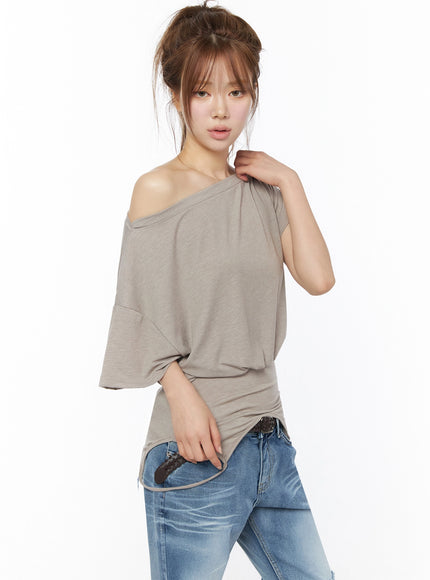 Off-Shoulder Two-Way Cami Top IU525 Beige three-quarter front shot on model with hand raised to shoulder highlighting off-shoulder neckline and draped jersey