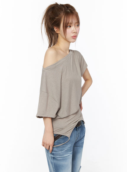 Off-Shoulder Two-Way Cami Top IU525 Beige side close-up shot on model showing bat-wing sleeve structure asymmetric shoulder and curved hem detail
