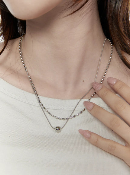 LEWKIN Olive Oval Necklace IL522 silver close-up on model showing layered oval bead chain and snake chain with ball pendant on white top
