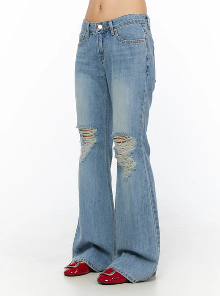 Olynn Low-Rise Distressed Flared Jeans CL513 Light blue side view on model showing low-rise waistband flare silhouette and knee distressing with canvas bag