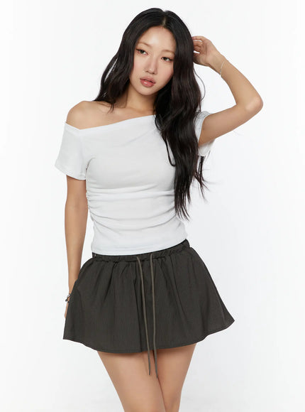 One-Shoulder Shirred Short Sleeve Top CU529 White front view on model with hand raised showing off-shoulder asymmetric neckline and ruched body