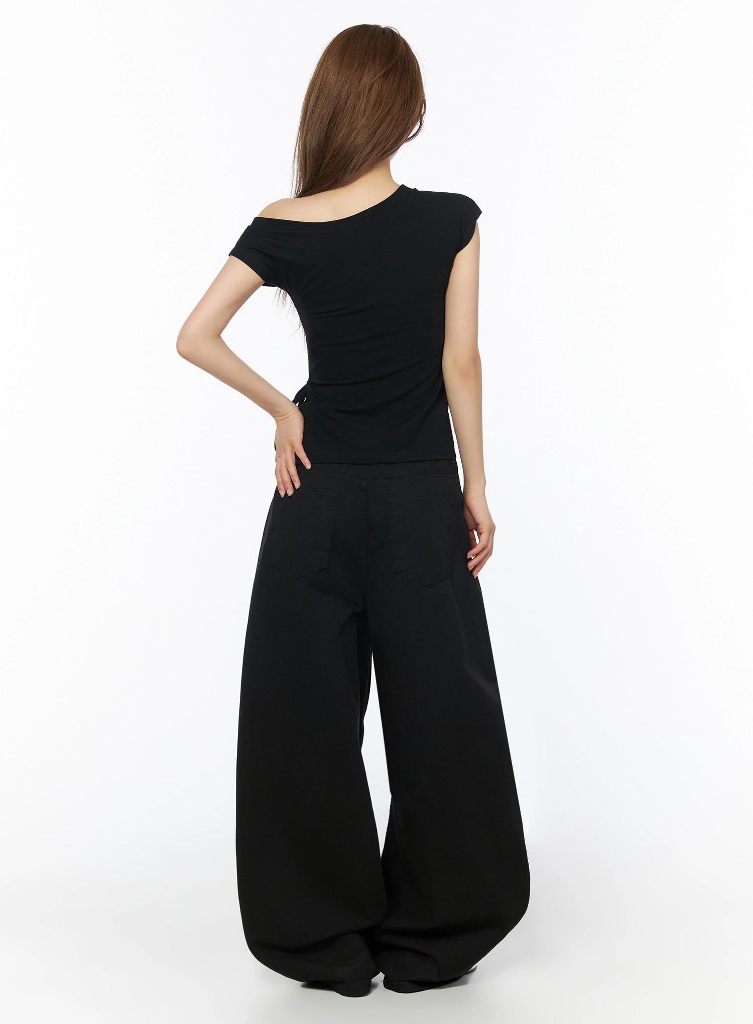 One-Shoulder Spiral Top IL502 Black back shot on model showing ruched back detail, asymmetric off-shoulder neckline, and side tie cutout with wide-leg pants