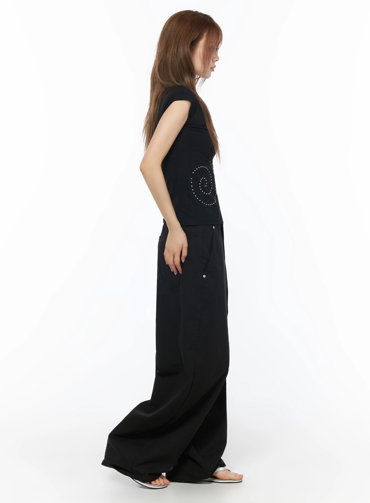 One-Shoulder Spiral Top IL502 Black side shot on model showing fitted silhouette with spiral stud detail and side cutout tie, paired with black wide-leg trousers