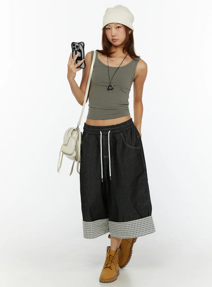 Open-Back Tank Top CL515 dark green full front outfit shot on model holding phone, styled with beanie, pendant necklace, white crossbody bag, and black wide-leg denim