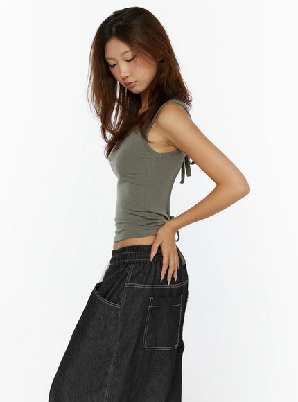 Open-Back Tank Top CL515 dark green side shot on model looking down, front scoop neckline and visible side tie detail, styled with dark denim drawstring pants
