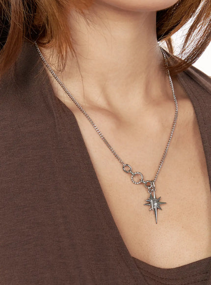 Orion Double Cross Necklace IL517 Silver close-up on model chest showing single north star charm with twisted ring connector on curb chain with brown top