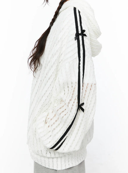 Oversized Bow Detail Windbreaker CU530 White side view on model with hood up headphones black bag leg raised gray shorts sneakers semi-sheer knit