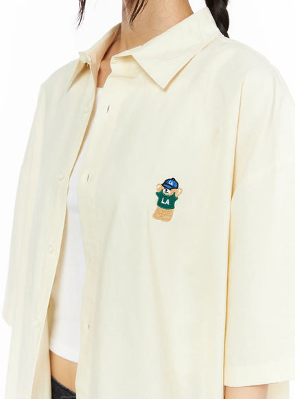 Oversized Button-Up Shirt CU530 Light yellow close-up chest detail shot on model showing LA bear mascot embroidery in green jersey and blue cap on left chest
