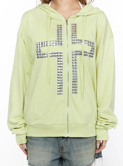 Oversized Cross Graphic Zip-Up Hoodie CL528 Light green close-up front model torso crop shot silver pyramid stud cross embellishment zip and ribbed hem detail