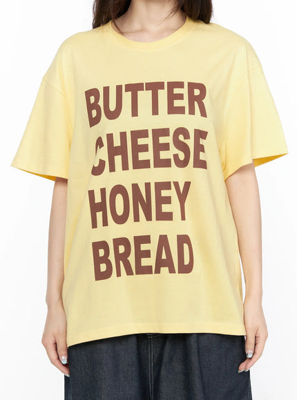 Oversized Graphic Tee CL522 Yellow close-up front on model showing full BUTTER CHEESE HONEY BREAD brown block-letter graphic print and crew neckline
