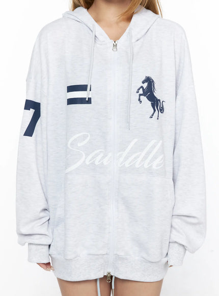 Oversized Graphic Zip-Up Hoodie CL528 Light Gray close-up detail front shot on model highlighting navy stripe panel navy horse graphic Saddle script and zip-up closure texture
