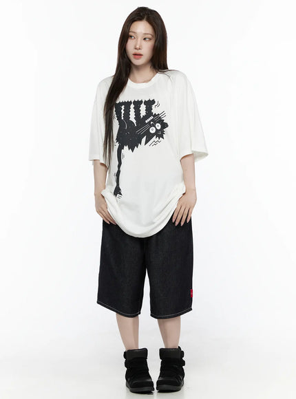 Oversized Kitty Graphic T-Shirt IL516 White full-body front shot female model hands pulling hem showing relaxed oversized fit styled with dark denim shorts and black sneakers