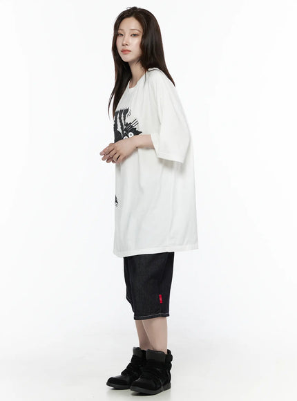 Oversized Kitty Graphic T-Shirt IL516 White side shot female model standing showing clean side profile dropped sleeve length and oversized silhouette with dark denim shorts