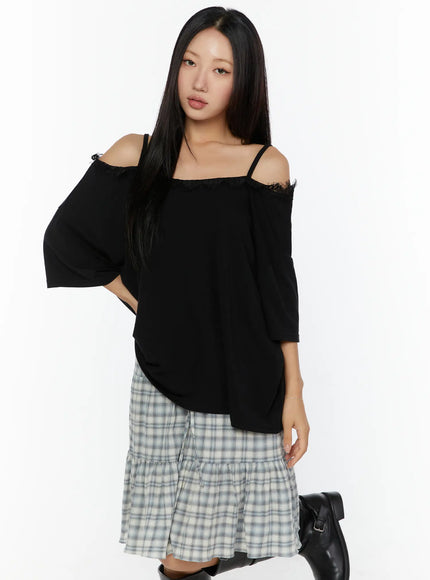 Oversized Lace-Detail Off-Shoulder Tee CU529 Black front shot on model with hand on hip paired with plaid tiered skirt and black boots