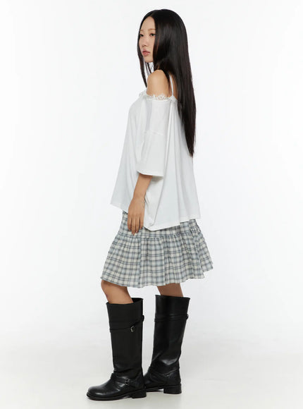 Oversized Lace-Detail Off-Shoulder Tee CU529 White side shot on model revealing cold-shoulder cut lace trim detail and boxy silhouette with plaid skirt