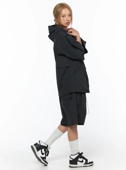 Oversized Plaid Windbreaker CU523 Black side shot model walking showing hooded jacket silhouette with layered hem detail grid fabric texture and matching shorts