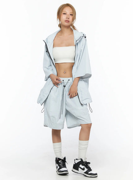 Oversized Plaid Windbreaker CU523 Light Blue full front shot model standing wearing open windbreaker over white bandeau top with matching light blue shorts and sneakers