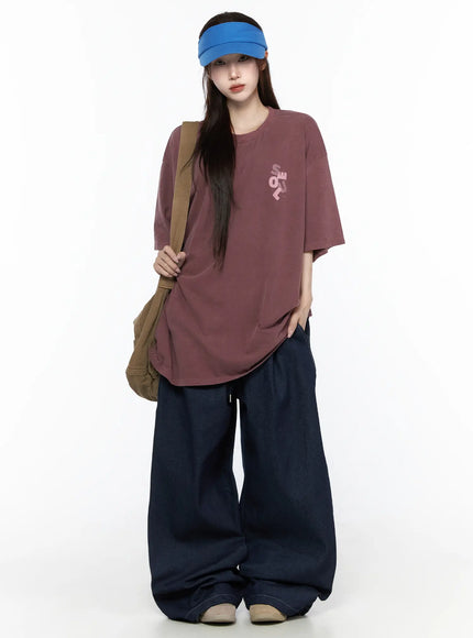 Oversized Seoul Graphic T-Shirt IL516 Dark red front full-body shot on female model with blue visor and canvas shoulder bag styled with wide-leg jeans