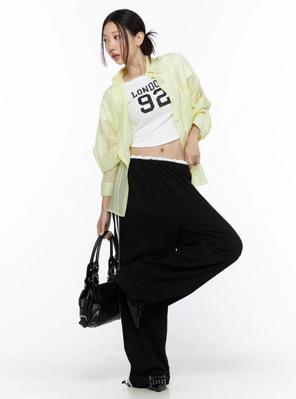Oversized Sheer Shirt CL524 Yellow three-quarter front model shot, open unbuttoned styling over crop top, holding black bag, one leg raised pose