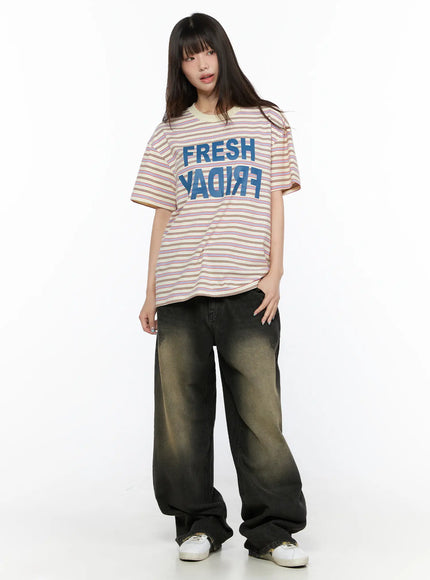 Oversized Striped Graphic Tee CL523 light beige full-length front model standing upright with blue FRESH FRIDAY mirrored print paired with wide-leg jeans