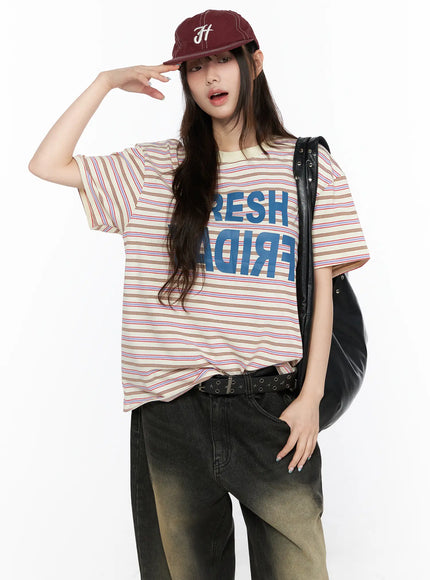 LEWKIN Oversized Striped Graphic Tee CL523 Light beige M/L front model styled shot with burgundy cap and black leather bag over wide-leg jeans
