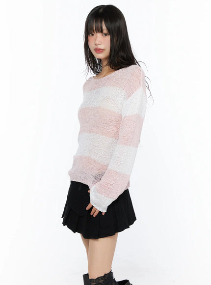 Oversized Striped Knit Sweater CU530 Pink three-quarter side front shot on model showing sheer knit stripe pattern flared cuffs and relaxed fit paired with black mini skirt
