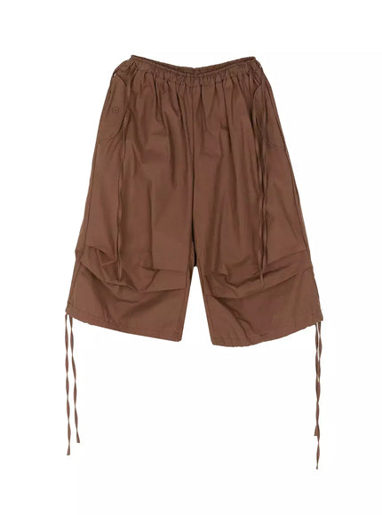 Parachute Cargo Shorts IU525 Brown flat-lay front showing elastic waistband, tiered wide-leg silhouette, button pocket, and ribbon drawstring ties at hem