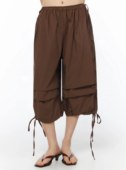 Parachute Cargo Shorts IU525 Brown front view on model with ties loosened showing wide balloon silhouette and layered hem panels, paired with sandals