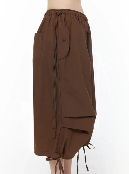 Parachute Cargo Shorts IU525 Brown side view on model showing curved patch pocket, button detail, drawstring waist, and tiered hem