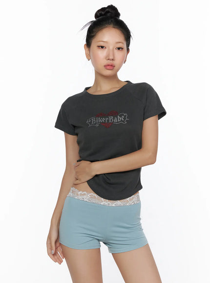 Pigment Cap Sleeve Tee CL510 Dark gray front model shot arms crossed showing rhinestone BikerBabe heart graphic slim cropped fit and curved hemline with lace shorts