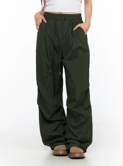 Pintuck Nylon Wide Pants CL514 Dark green front close-up on model with hands in pockets showing drawstring waist pintuck pleats and wide nylon leg
