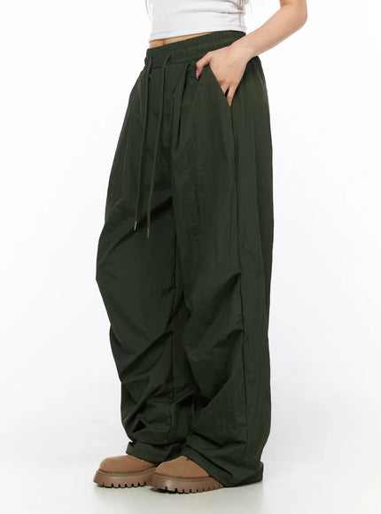 Pintuck Nylon Wide Pants CL514 Dark green side view on model standing hand in pocket showing wide-leg silhouette and drawstring waist