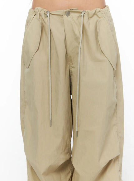 Pintuck Pocket Parachute Pants CU524 Beige close-up detail shot of waistband showing drawstring cords silver aglets button closure and pintuck pleating