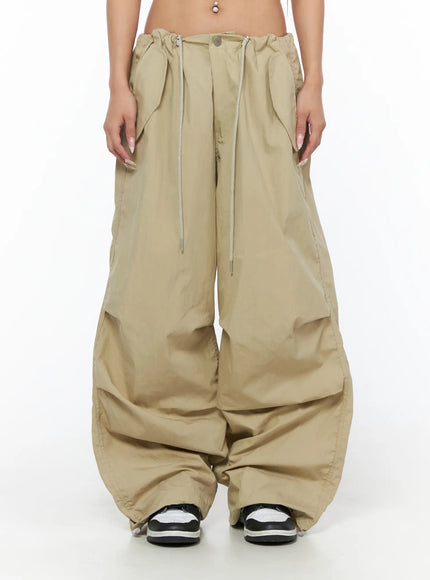 LEWKIN Pintuck Pocket Parachute Pants CU524 Beige front crop shot on model showing drawstring waistband pleats and wide-leg nylon silhouette with pooling hem