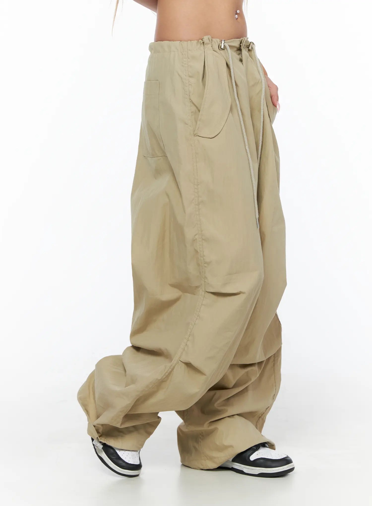 Pintuck Pocket Parachute Pants CU524 Beige side shot on model showing drawstring waist side pocket detail and voluminous wide-leg nylon fabric