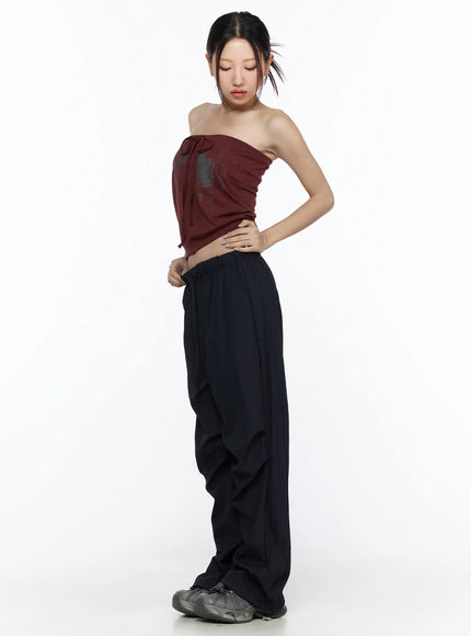 Pintuck Wide Leg Pants CL527 Dark blue side model shot model looking down adjusting elastic waistband, showing draped parachute fabric volume