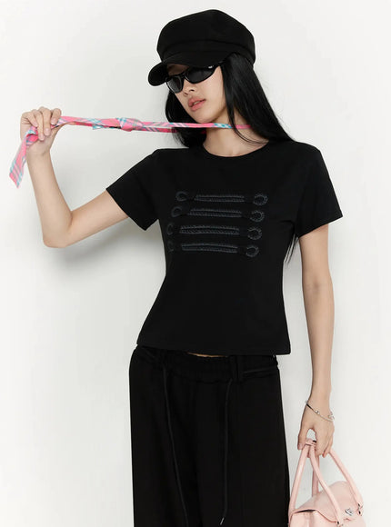 Plaid Adjustable Tie IL516 Pink front shot on model holding plaid tie strap upward revealing black military-embroidered crop tee styled with black wide-leg trousers and baker boy cap