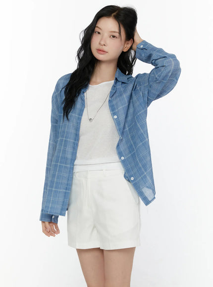 Plaid Button-Up Shirt CL521 Blue front shot on model with one hand raised to hair, open over white tee and white shorts, casual pose highlighting sleeve detail